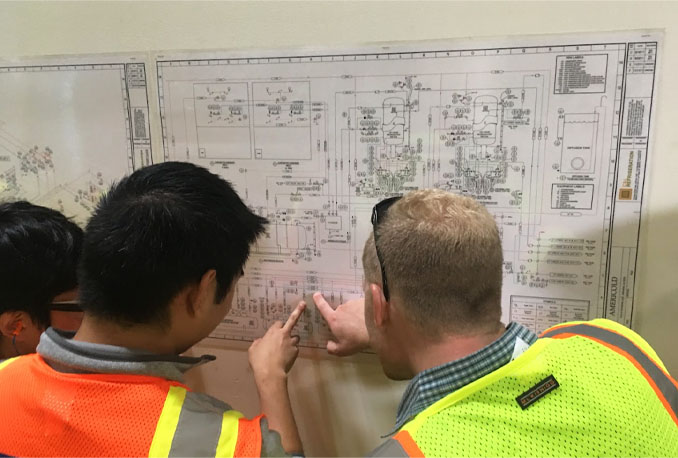 image of two students looking at a project layout on wall.