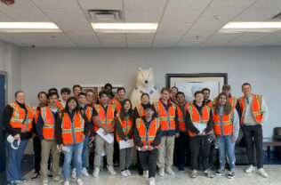 group of students wearing orange safety vests smiling for a photo.